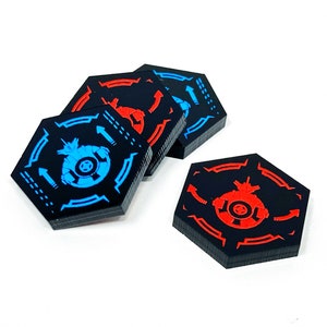 May include: Four hexagonal game tokens with black backgrounds and red and blue accents. The tokens feature a stylised spaceship design with arrows pointing in different directions.