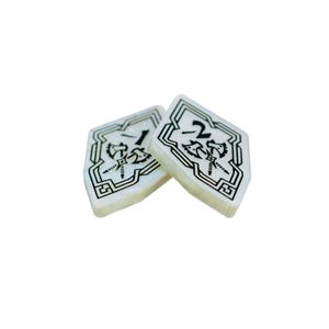 May include: Two white, diamond-shaped game pieces with black markings. The pieces are numbered "1" and "2".