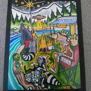 May include: A colorful, whimsical painting depicting a campsite scene with cartoon animals and an alien. A bear, raccoon, and moose are gathered around a campfire, with an alien holding a cup. An alien spaceship hovers above the scene. The painting is framed in black.