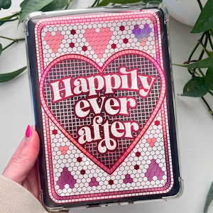 May include: A clear e-reader case featuring a mosaic heart design. The heart is pink with a red outline, and the words "Happily ever after" are in white script. The background is a mix of pink, purple, and white tiles.