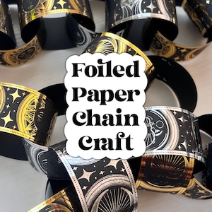 May include: Close-up of a foiled paper chain craft. The paper chain links are black with gold and silver celestial designs. The text "Foiled Paper Chain Craft" is in a white cloud-shaped text box.
