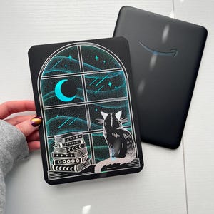 May include: A black cat sits in a windowsill looking out at a starry night sky with a crescent moon. A stack of books sits on the windowsill below the cat. The image is printed on a black card with a holographic finish.