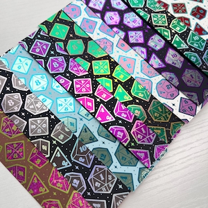 May include: A selection of patterned bookmarks with dice designs in various colours. Each bookmark showcases a different colour scheme, including black, blue, pink, green, and purple, with metallic highlights. The dice are of different shapes and sizes, adding visual interest.
