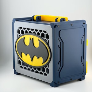 Peut inclure: Une boîte bleue et jaune avec un logo Batman sur le devant. La boîte a une poignée et un loquet.