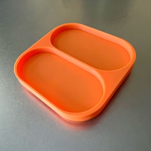 May include: Orange plastic tray with two oval-shaped compartments.