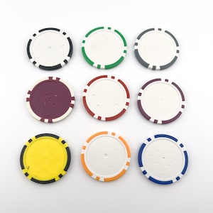 Puede incluir: Nueve fichas de póquer redondas con centros blancos y anillos exteriores de diferentes colores. Las fichas están dispuestas en tres filas de tres. Los colores son negro, verde, gris, granate, rojo, blanco, amarillo, naranja y azul.