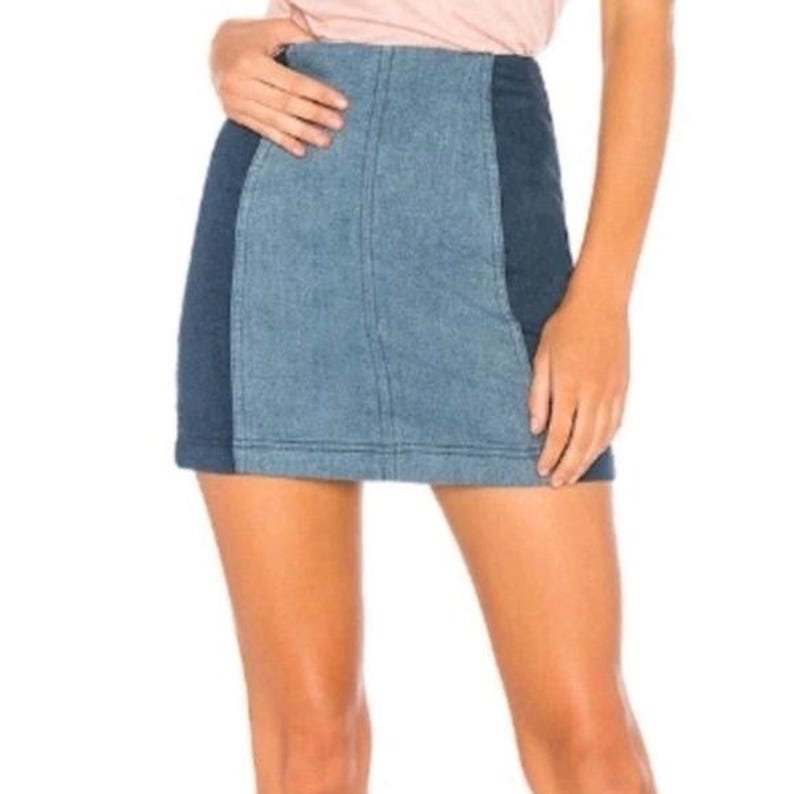 Puede incluir: Minifalda vaquera con dise&ntilde;o de bloques de color. La falda presenta un panel central azul claro flanqueado por paneles laterales azul oscuro. La falda es de estilo casual, adecuada para el uso diario.