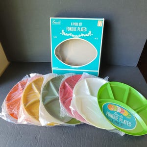以下が含まれることがあります： オレンジ、黄色、緑、赤、白、緑の6色のプラスチック製フォンデュプレートのセット。プレートは透明なプラスチックで包装されており、「Grants 6 Piece Set Fondue Plates」と書かれたティールボックスが付属しています。