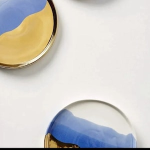 Puede incluir: Dos platos redondos de cer&aacute;mica con un dise&ntilde;o azul y dorado. Los platos tienen un acabado liso y brillante y un borde ligeramente elevado.