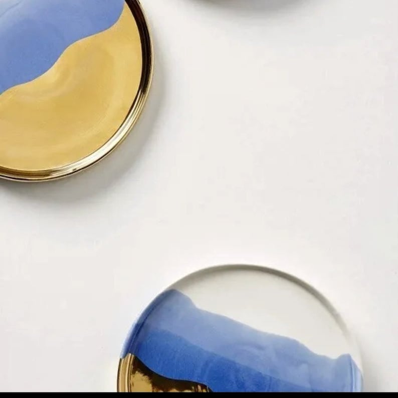 Puede incluir: Dos platos redondos de cer&aacute;mica con un dise&ntilde;o azul y dorado. Los platos tienen un acabado liso y brillante y un borde ligeramente elevado.