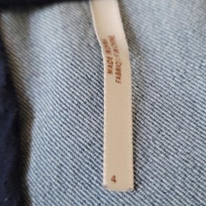 Puede incluir: Primer plano de una etiqueta de ropa color crema con el texto "MADE IN CHINA FABRIQU&Eacute; EN CHINE" y el n&uacute;mero "4". La etiqueta est&aacute; adherida a una tela vaquera azul.