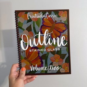 May include: A brown spiral bound book with the title "Outline Stained Glass Volume Two" and a colorful stained glass design featuring butterflies and flowers.
