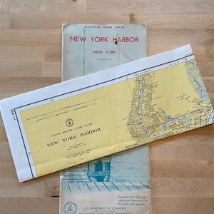 May include: A vintage nautical chart of New York Harbor, showing the waterways and islands around the city. The chart is titled "New York Harbor" and includes the text "United States - East Coast" and "Boundries in Feet".