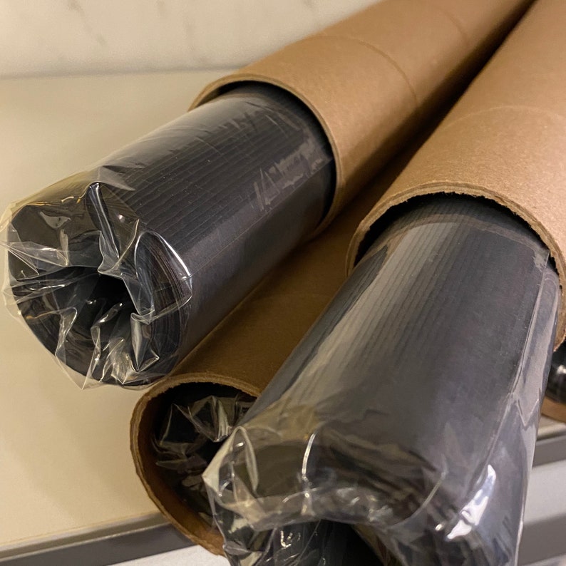 May include: Two rolls of black fabric wrapped in brown cardboard tubes. The fabric is wrapped in clear plastic.