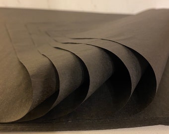 May include: A stack of black tissue paper, folded and layered, creating a textured and abstract pattern.