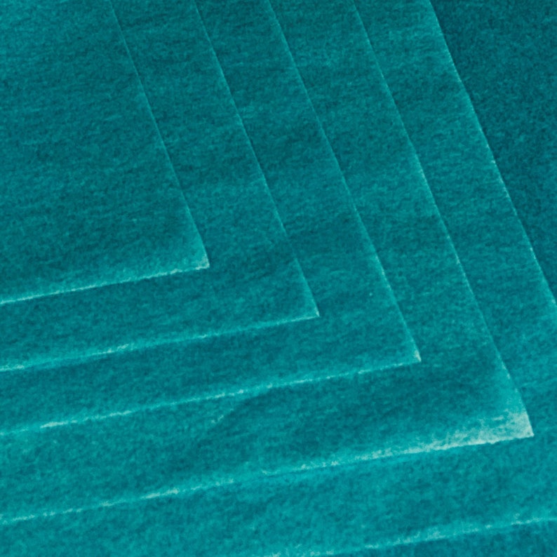 May include: A stack of teal-colored felt sheets, arranged in a layered pattern. The sheets have a slightly textured surface and are angled to create a geometric design. The color is a vibrant, saturated teal.