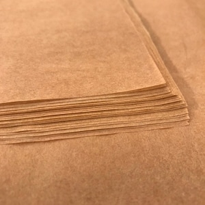 以下が含まれることがあります： 茶色の薄紙のシートの束。紙は薄くて半透明で、わずかにざらざらした質感です。