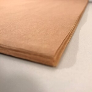 以下が含まれることがあります： 端が綺麗に折り畳まれた、茶色の紙の束