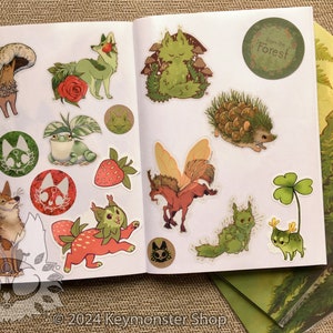 May include: A sticker sheet with a variety of nature-themed illustrations, including a fox, a frog, a hedgehog, a mushroom, a strawberry, a fairy, and a clover. The sheet also includes a sticker that says "From the Forest!"