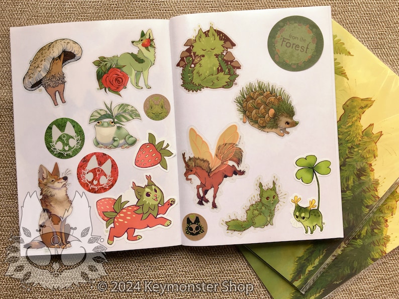 May include: A sticker sheet with a variety of nature-themed illustrations, including a fox, a frog, a hedgehog, a mushroom, a strawberry, a fairy, and a clover. The sheet also includes a sticker that says "From the Forest!"