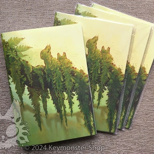 May include: A set of five cards featuring a whimsical illustration of two green, furry creatures sitting on a branch with hanging ferns. The background is a soft yellow with a green gradient.