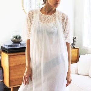May include: A white sheer nightgown with a lace overlay and short sleeves. The nightgown is loose-fitting and has a gathered neckline.