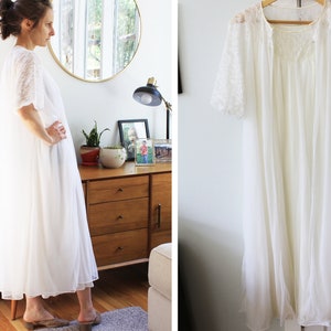 May include: White lace robe with short sleeves and a V-neckline. The robe is made of a sheer fabric and has a flowing silhouette.