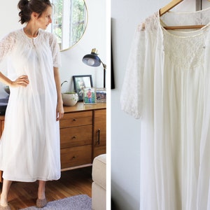 May include: White lace nightgown with a long, flowing skirt and short sleeves. The gown is made of a sheer fabric and has a delicate lace trim.