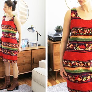 May include: A sleeveless red, green, and yellow striped dress with a floral pattern. The dress has a scoop neck and a straight hemline.