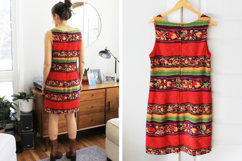 May include: A sleeveless red dress with a colorful striped pattern featuring green, yellow, purple, and orange accents. The dress has a scoop neck and a straight silhouette.