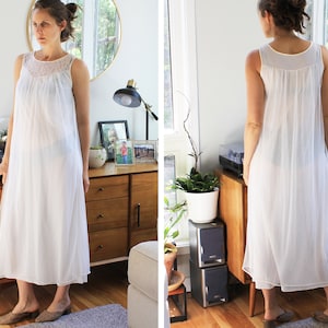 May include: A white sleeveless nightgown with a lace trim around the neckline. The nightgown is made of a sheer fabric and has a flowing silhouette.