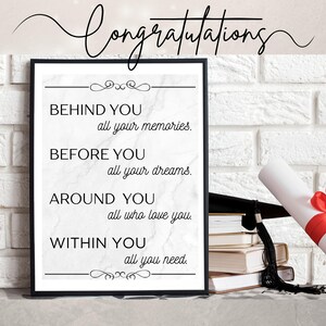 May include: A framed print with the word "Congratulations" in cursive script. The print features inspirational text: "Behind you all your memories. Before you all your dreams. Around you all who love you. Within you all you need." A graduation cap, books, and a diploma are also visible.