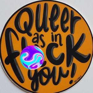 Puede incluir: Una pegatina redonda con el texto "Queer as in F*ck you!" en negro sobre un fondo naranja. Un diseño colorido y arremolinado está en el centro. Un diseño llamativo y colorido.