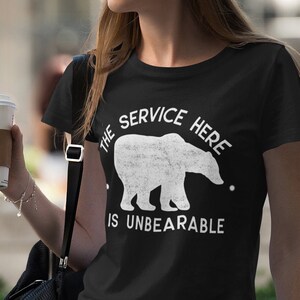 May include: A black t-shirt with a white graphic of a polar bear and the text "The service here is unbearable".