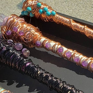 May include: Three copper wire wrapped wands with amethyst and turquoise beads. The wands are wrapped in different colors of wire, including black, copper, and white.