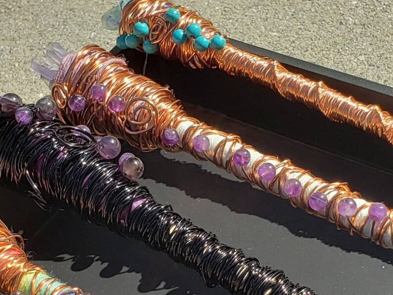 May include: Three copper wire wrapped wands with amethyst and turquoise beads. The wands are wrapped in different colors of wire, including black, copper, and white.