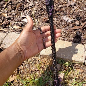May include: A black wire-wrapped wand with purple amethyst crystals and a clear crystal point at the top.
