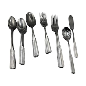 May include: A collection of stainless steel silverware, including spoons, forks, and a butter knife, arranged on a white surface. The spoons have a rounded bowl and a long, ridged handle. The forks have four tines. The butter knife has a flat, rounded blade.