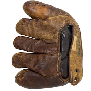May include: A vintage baseball glove in shades of brown, with visible wear and tear. The glove features individual finger stalls and a pocket for catching the ball. The leather shows signs of age, with stitching and eyelets for laces.