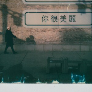 May include: A brick wall with two signs on it. The top sign says "you are beautiful" and the bottom sign says "你很美丽" in Chinese characters. A person is walking in front of the wall.