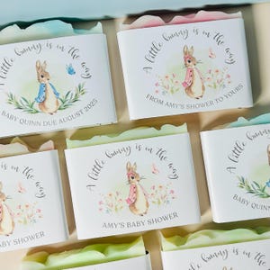 May include: Several white boxes with a watercolor illustration of a bunny, butterflies, and floral accents. Text reads "A little bunny is on the way" and "Baby Quinn due August 2025". Some boxes say "Amy's Baby Shower".