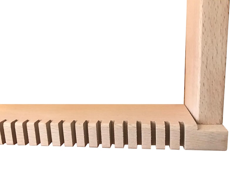 May include: Close-up of the bottom edge of a wooden frame with a series of evenly spaced slots cut into the wood.