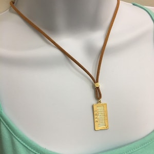 May include: A gold necklace with a brown suede cord and a rectangular pendant that says "LOVE" and has a barcode design.