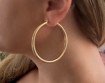 May include: A pair of large, gold hoop earrings. The earrings are thick and have a smooth, polished finish.