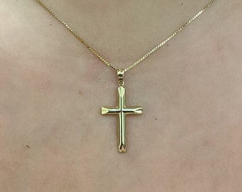 May include: A gold chain necklace with a simple gold cross pendant.