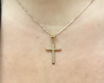 May include: A gold chain necklace with a simple gold cross pendant.