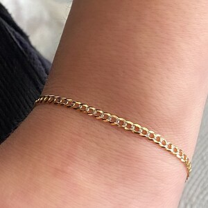 May include: A gold chain bracelet with a curb link design.