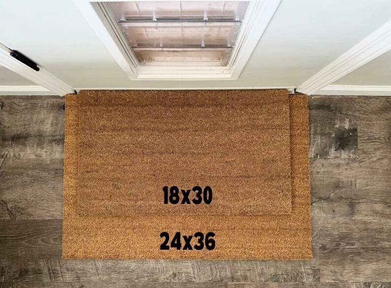 May include: Two brown coir doormats with black text. The smaller mat is labeled "18x30" and the larger mat is labeled "24x36".