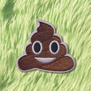 May include: Embroidered patch of a smiling poop emoji. The patch is brown with a light purple border, black eyes, and a white smile. The patch is set against a green, fluffy background.