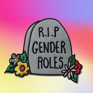 Peut inclure: Une pierre tombale grise avec le texte "R.I.P. Gender Roles" brodé dessus. La pierre tombale est décorée de fleurs brodées colorées.